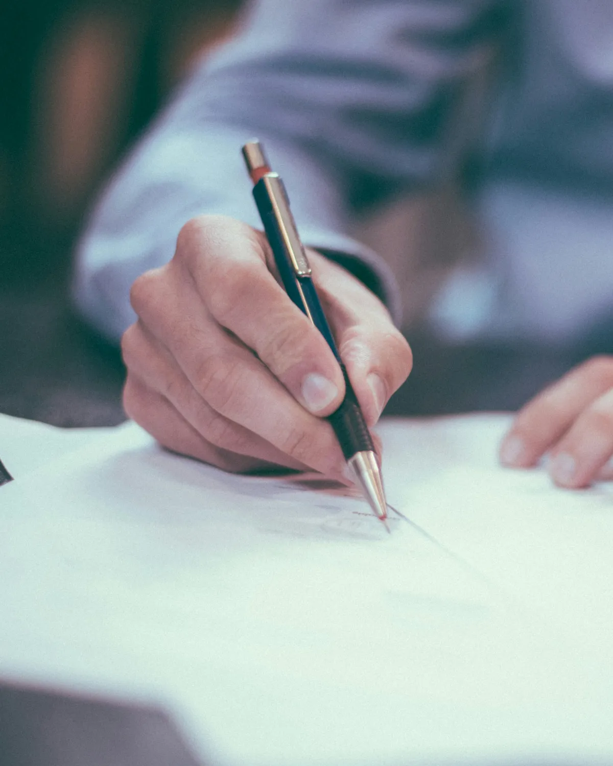 A hand reviewing and marking up a document at the desk