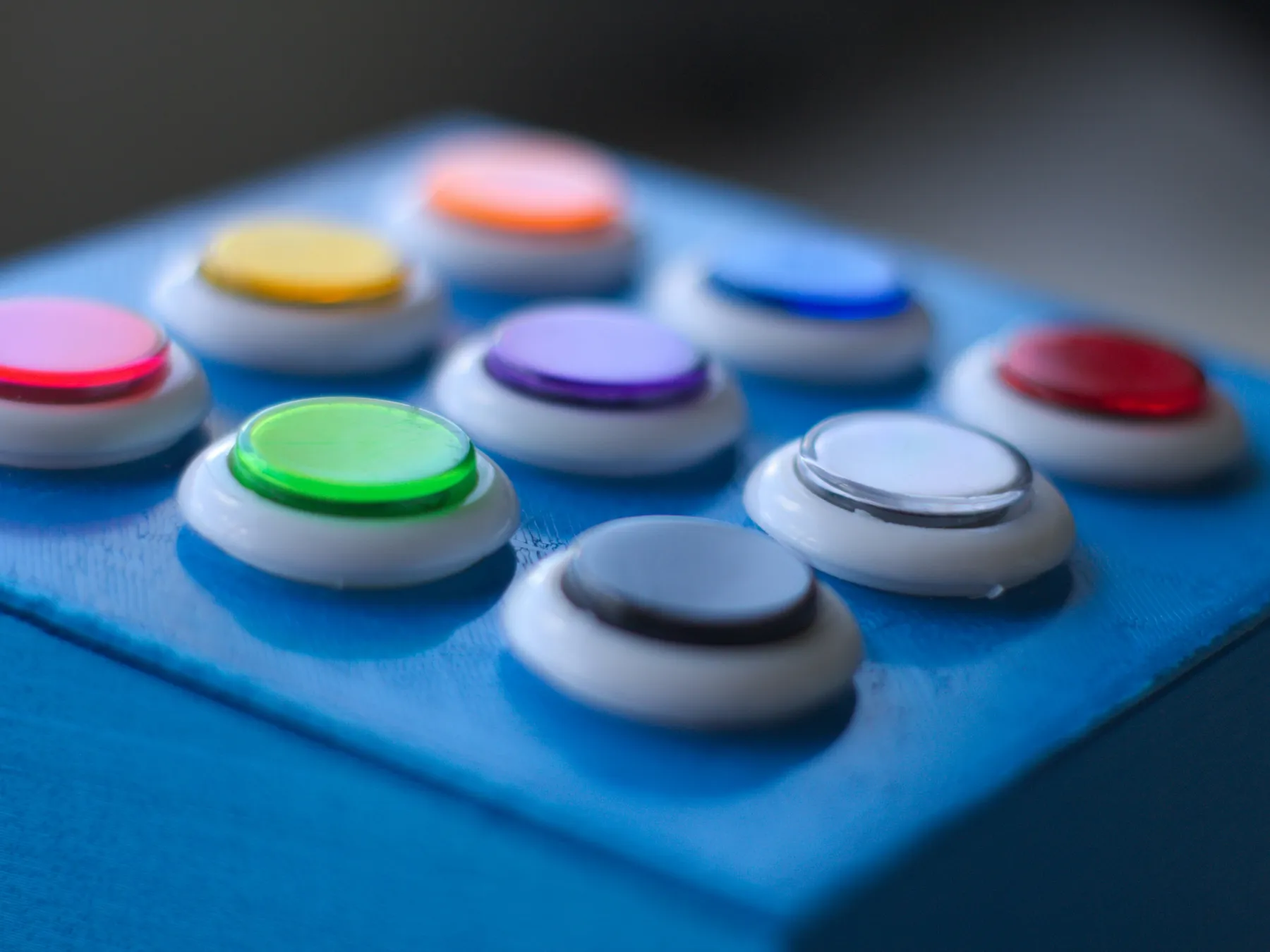 Close-up of a row of rainbow-colored arcade buttons on a blue block