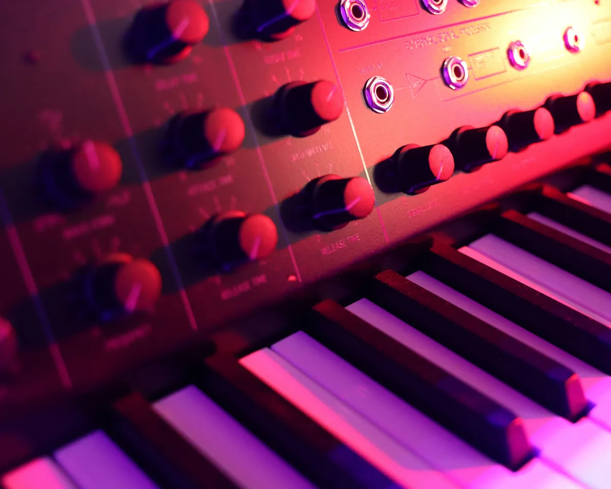 Close-up of a red-lit retro synthesizer's knobs and keys