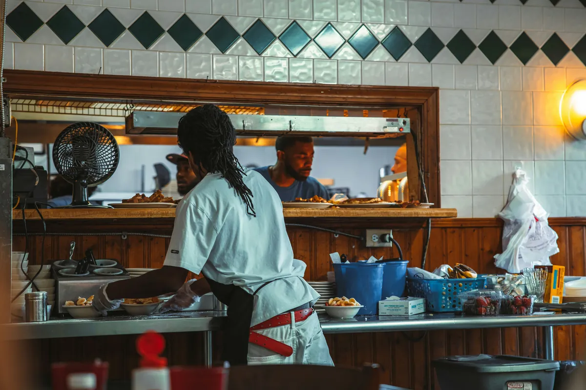 Cook plating breakfast at the kitchen pass window
