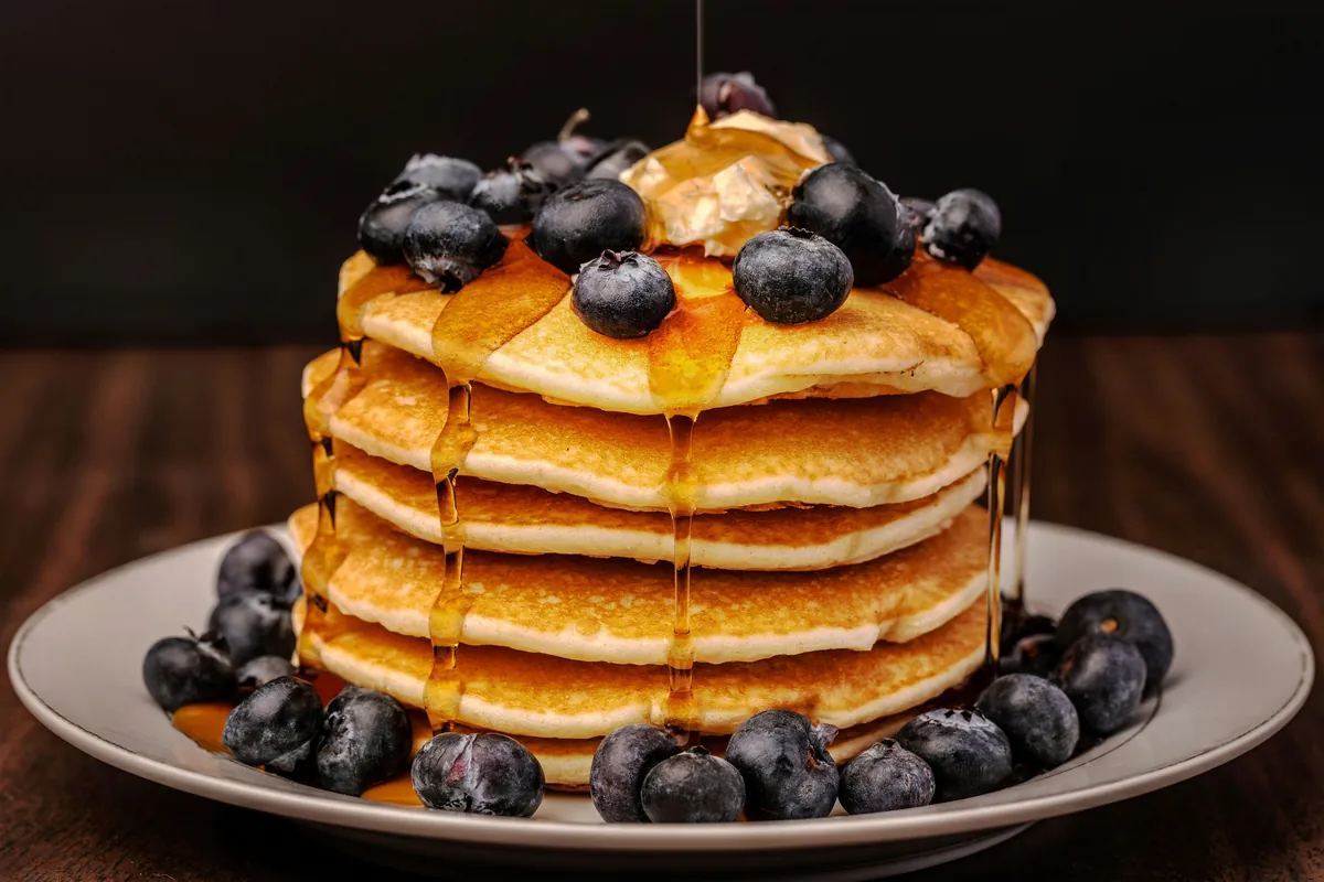 Stack of buttermilk pancakes with blueberries and warm syrup