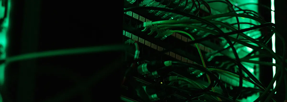 Tangle of network cables lit by green LED light in a server rack