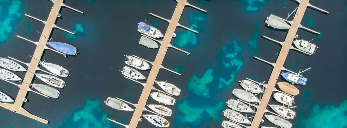 Aerial view of a marina, sailboats docked in clear turquoise-edged water