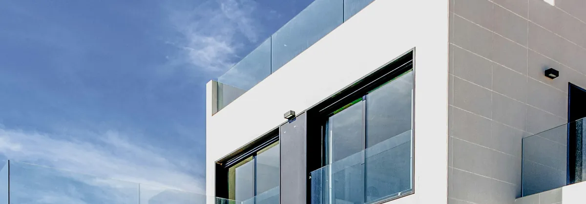 Geometric modern house facade with dark-framed glass and a rooftop railing