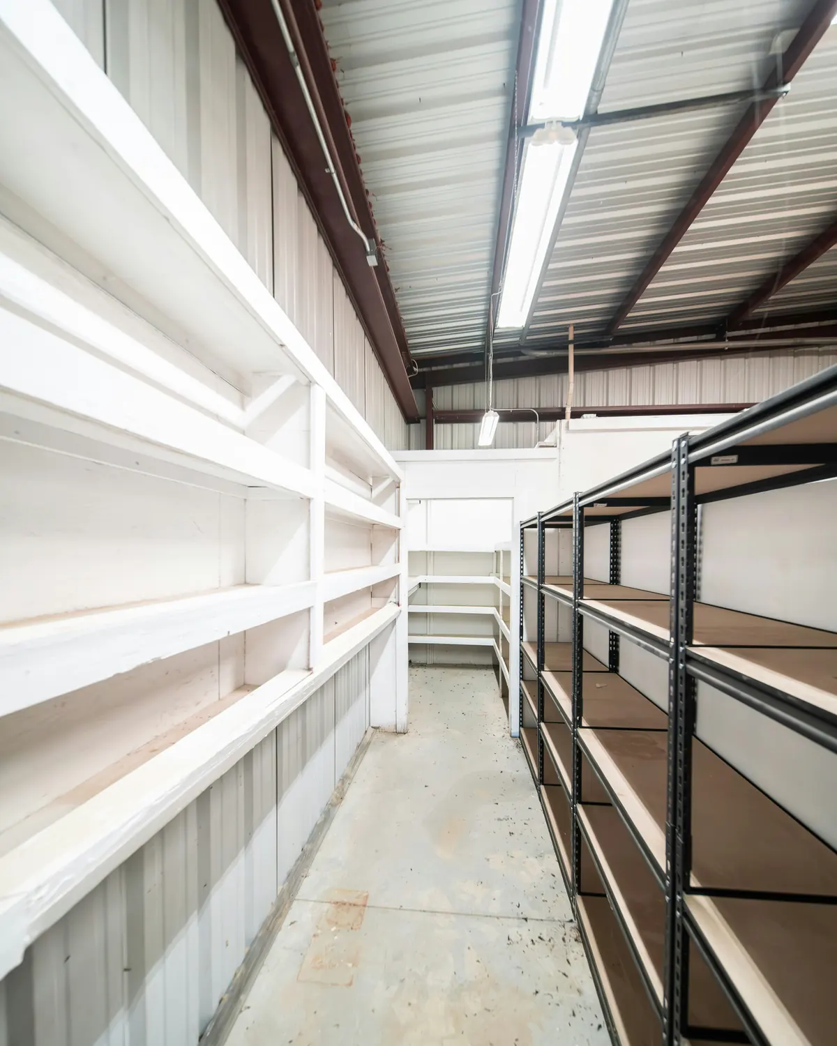 Warehouse storage aisle with empty steel shelving and a loading corridor