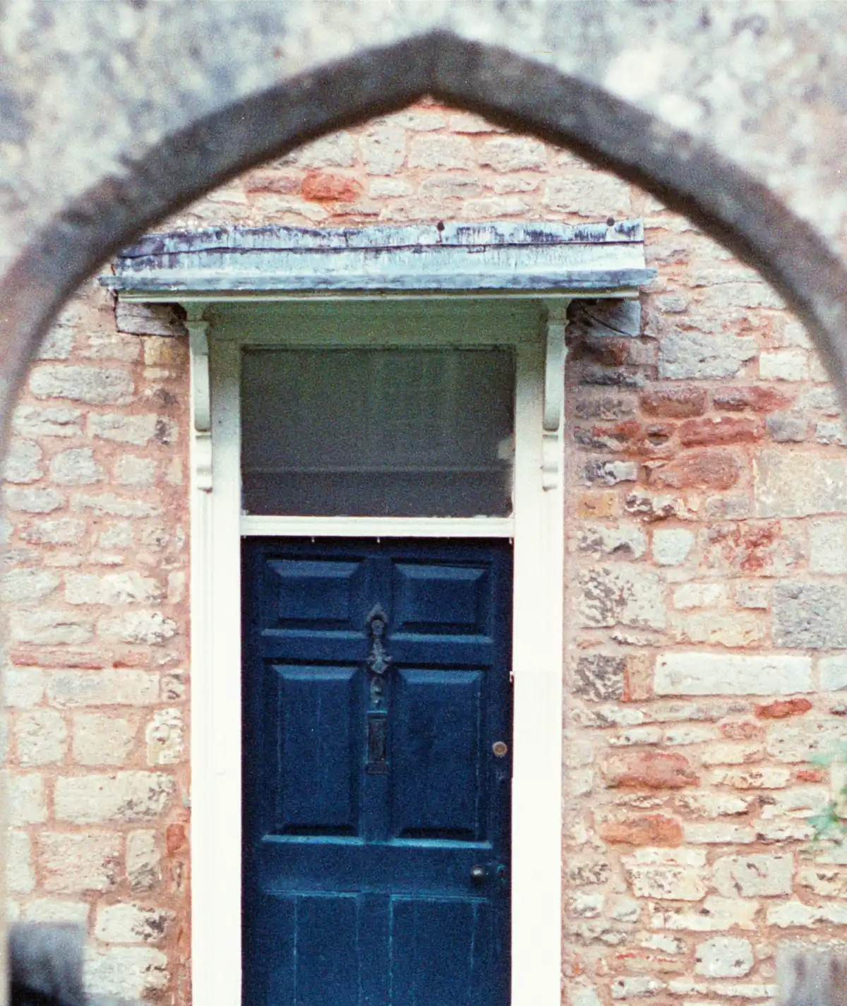 The firm's arched stone entrance and dark blue door, seen through an outer archway.